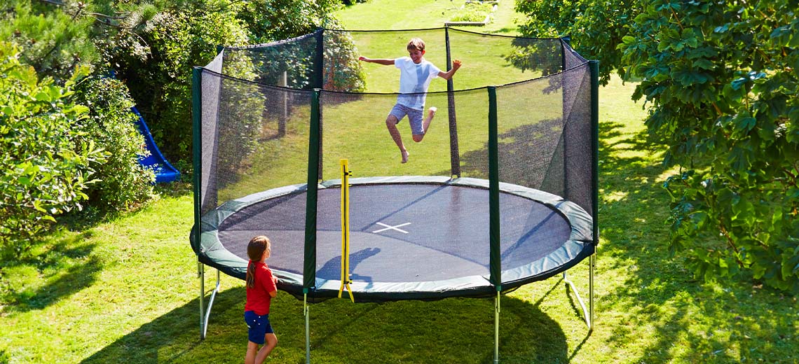 Bahçedeki büyük trambolinde oynayan çocuklar