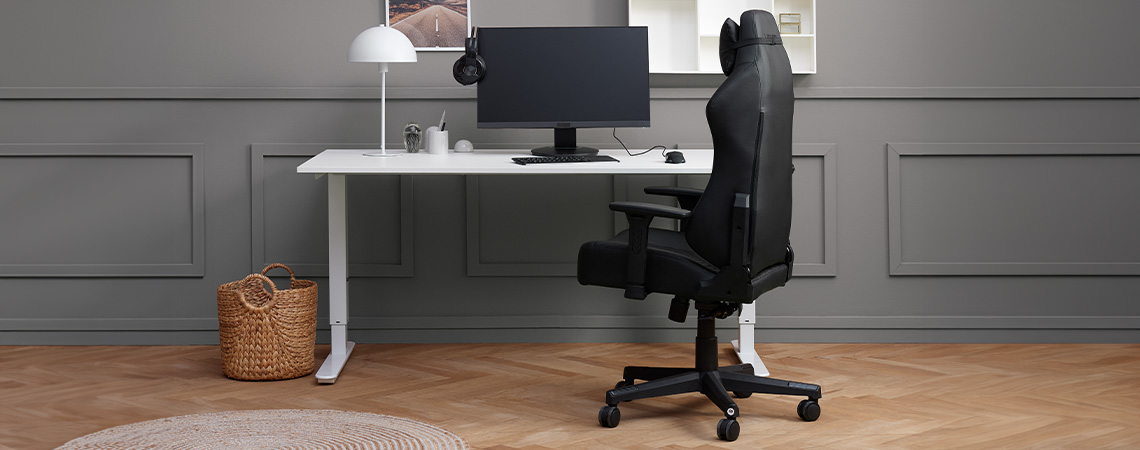Monitör ve kulaklıklı bir masanın yanında şık, zarif ve ergonomik oyun koltuğu