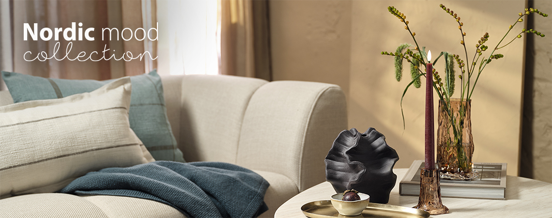 Kanepe, cam vazo ve şamdan bulunan sehpalı bir oturma odası