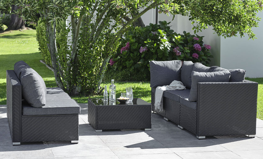 Siyah modüler bahçe mobilyası, bir salon masası ile ayrılmış, birbirine bakan iki kanepe olarak yapılandırılmıştır 