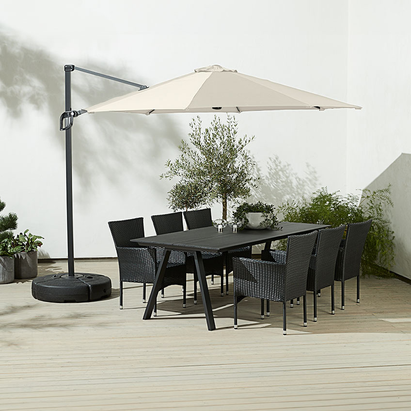 Bahçe sandalyeleri ile açık hava yemek masasının üzerinde büyük, kare, kirli beyaz asılı şemsiye