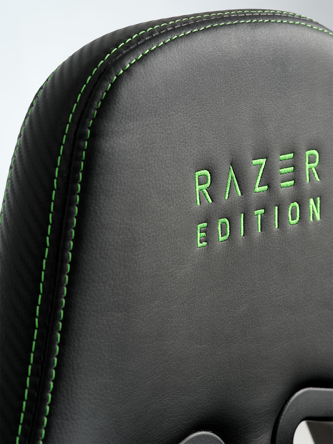 TYPE Z – RAZER EDITION™ BY LEGEND oyun koltuğu Sırt kısmında yeşil renkte "RAZER EDITION" yazısı bulunan, yeşil dikişli siyah bir Razer oyun koltuğunun yakın çekimi.